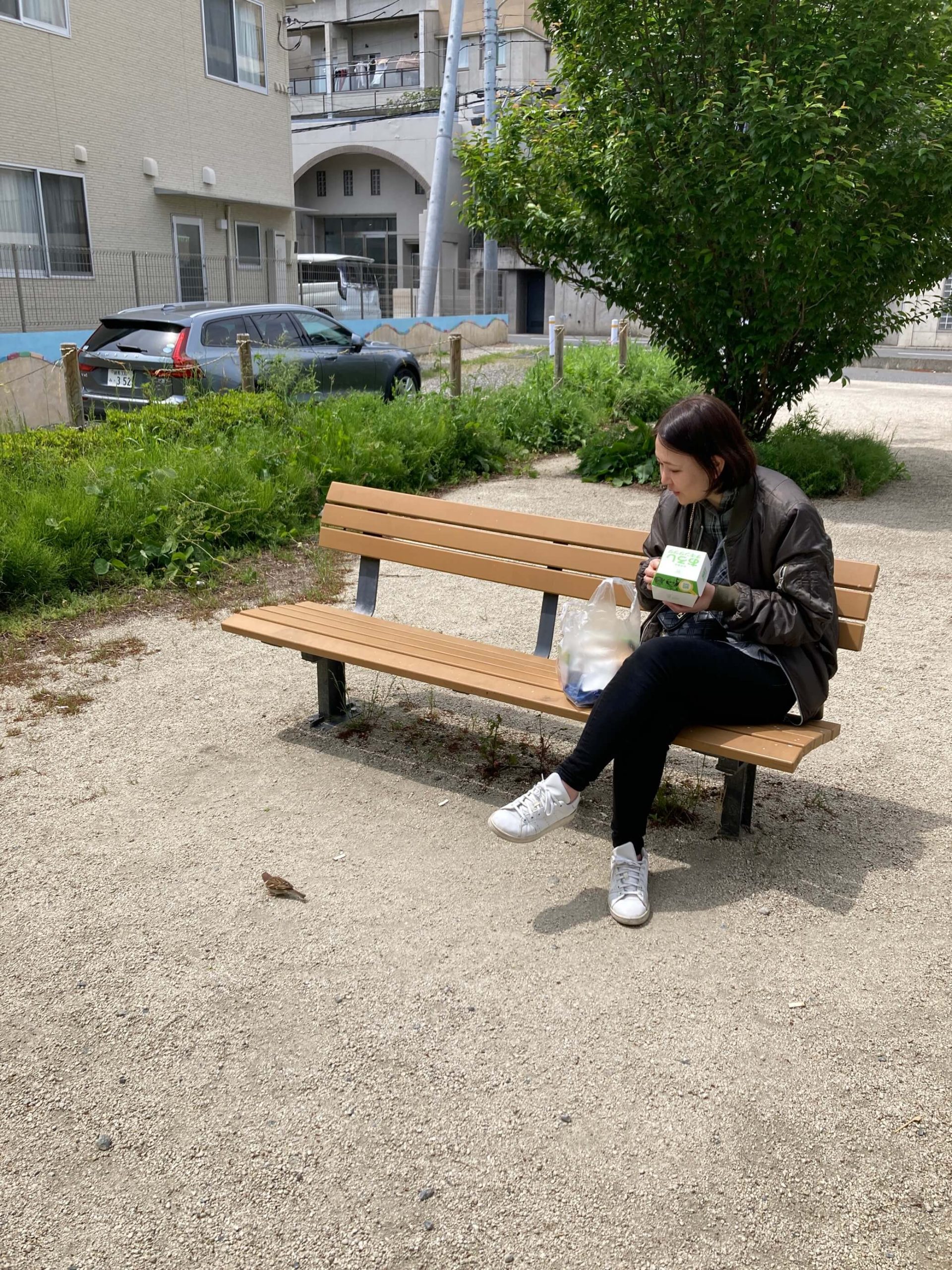 公園のベンチに座っている女性  中程度の精度で自動的に生成された説明